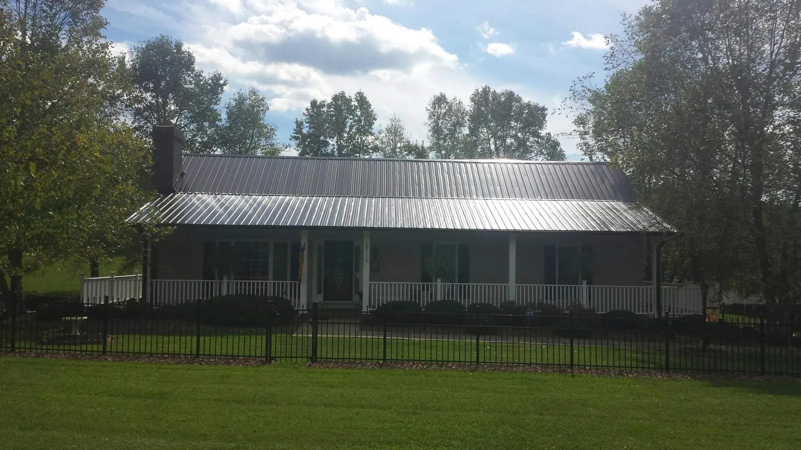Gray metal roof on a brick ranch with a full width front porch — Gutter Guard Installation work by our crew in Hastings